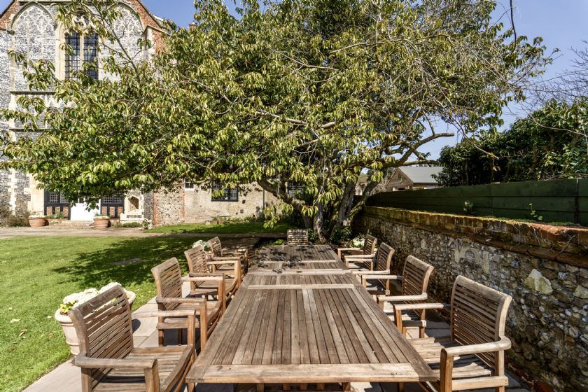 Outdoor wooden dining table with chairs under large tree