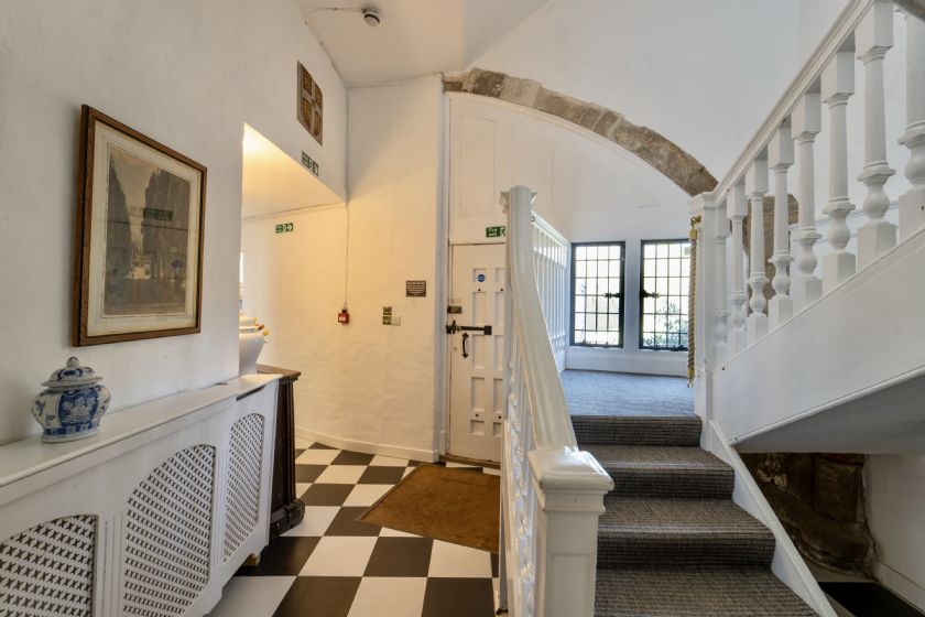 Interior hallway with checkered floor, white walls and staircase