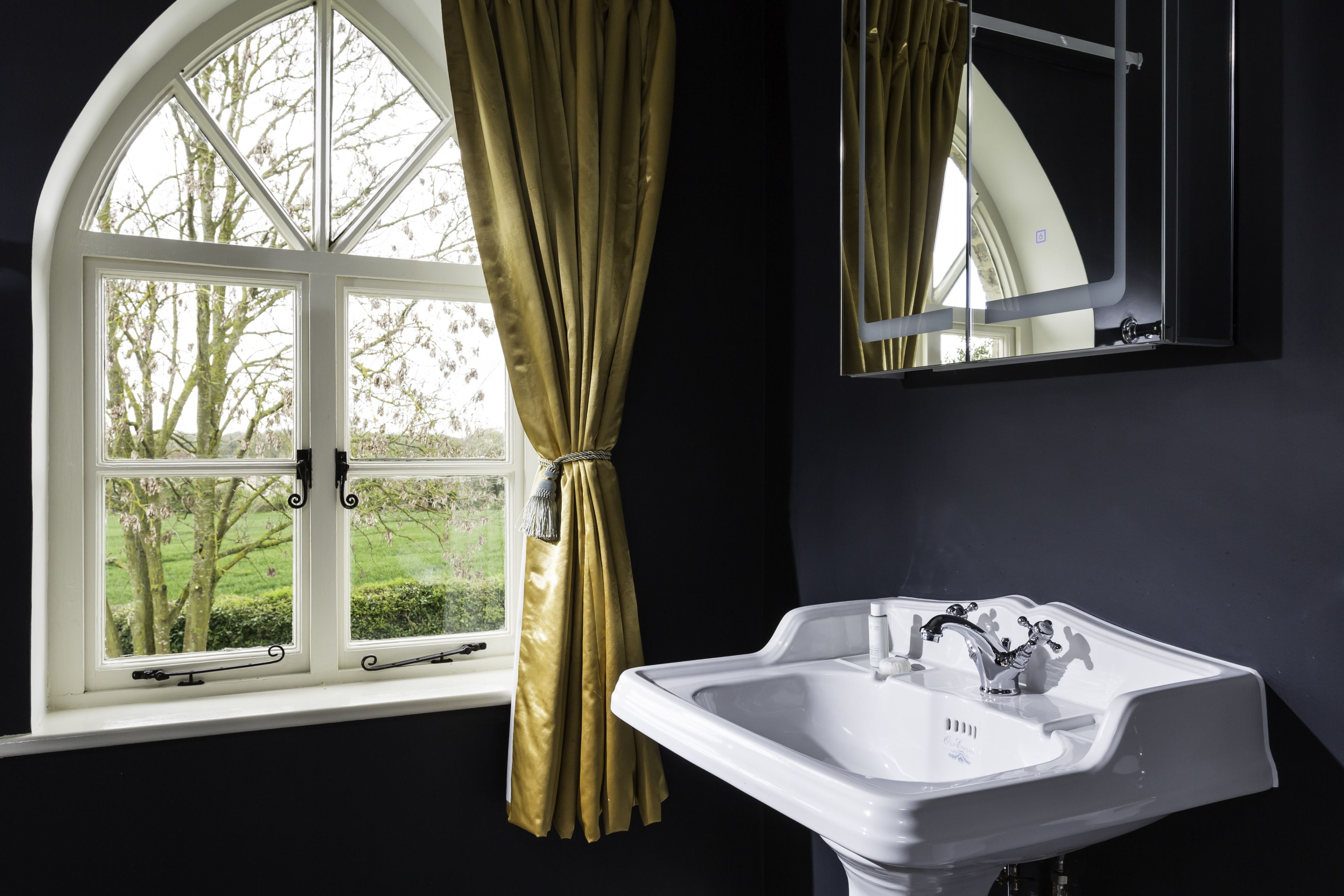 Elegant bathroom with arched window and gold curtain