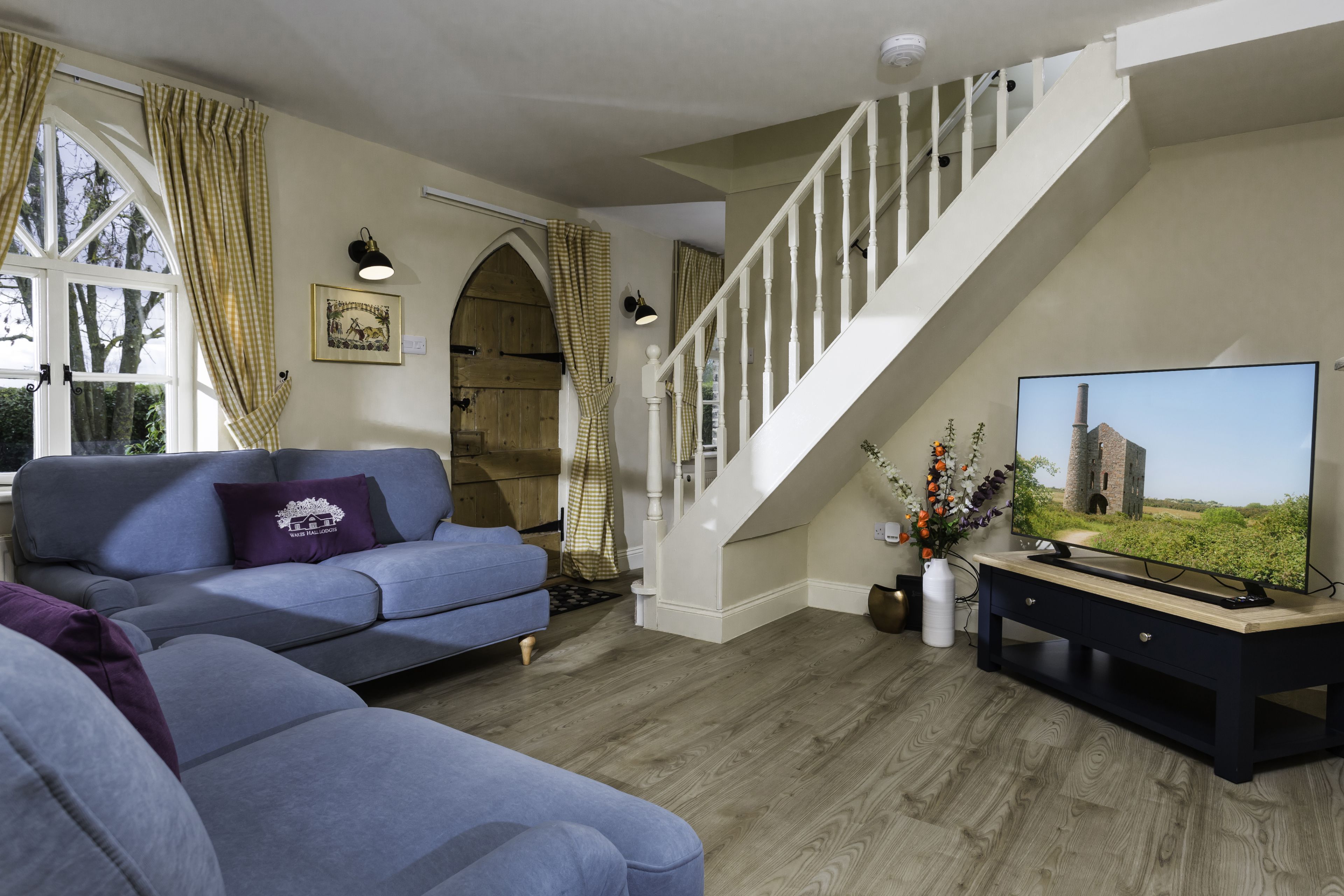 Living room with blue sofas, wooden staircase and arched doorway