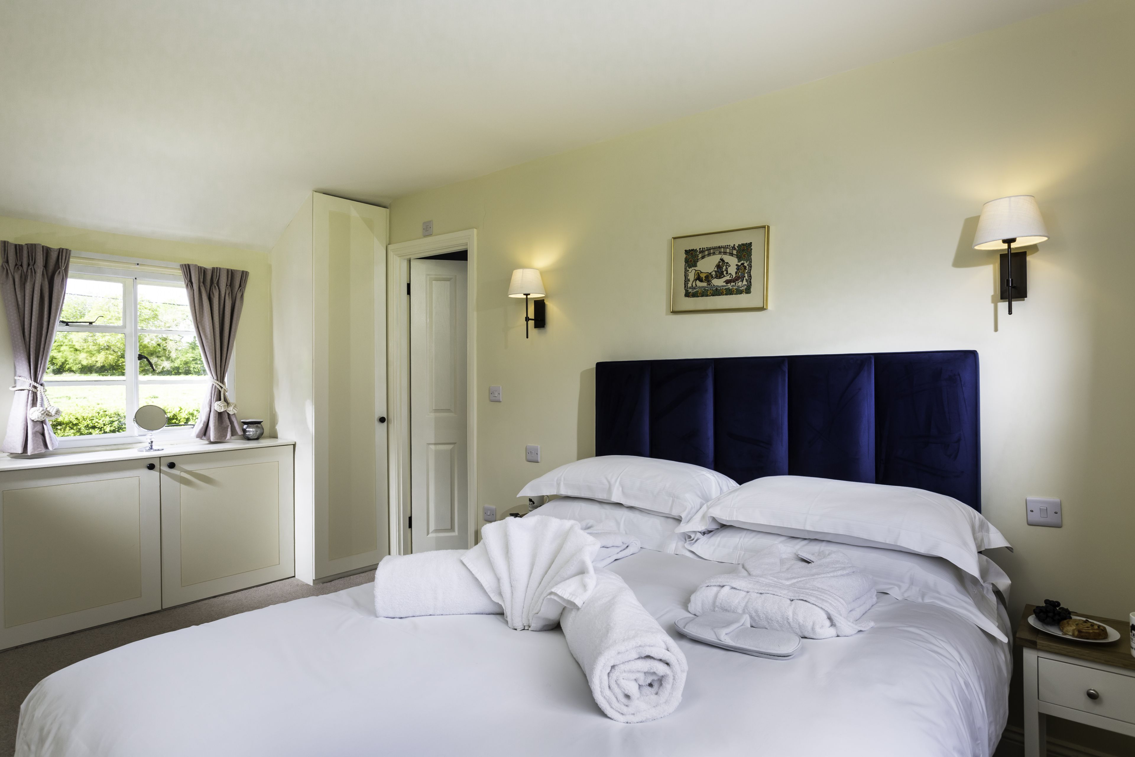 Bedroom with navy blue headboard and white bedding