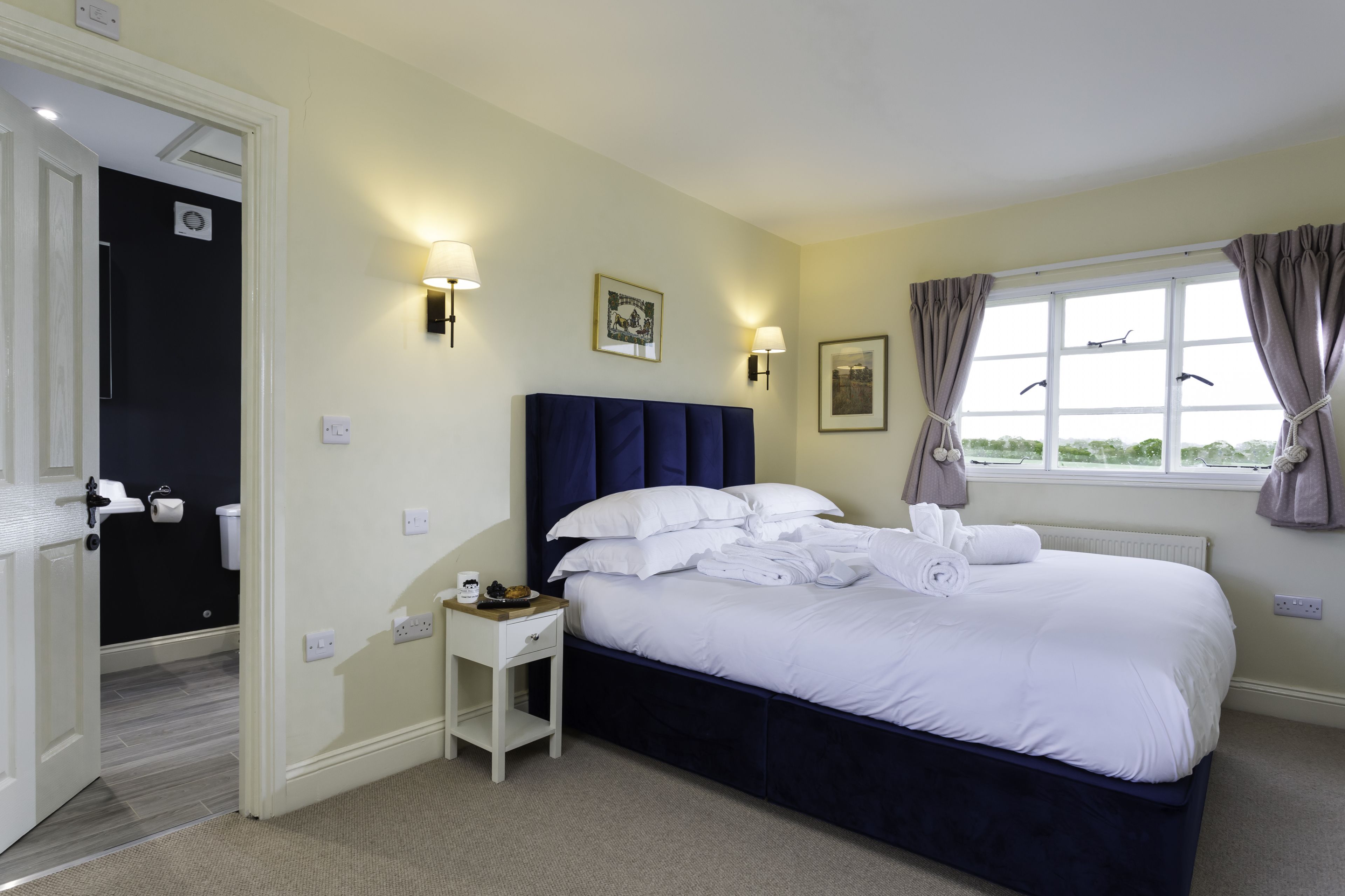 Bedroom with navy headboard and bathroom entrance