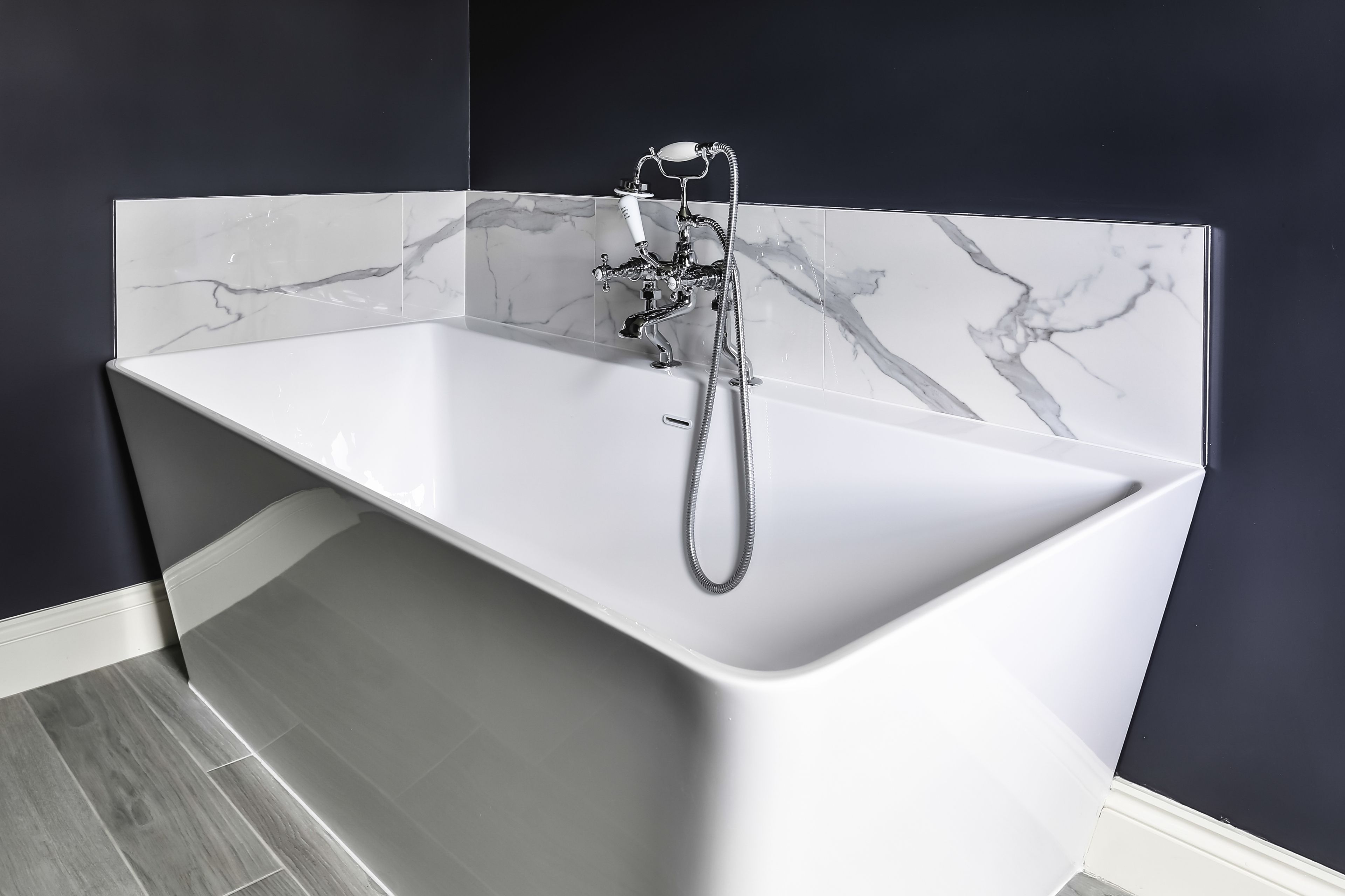 Freestanding bathtub with marble-effect backsplash