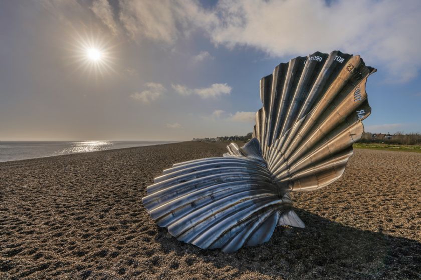 Metal scallop shell sculpture on beach
