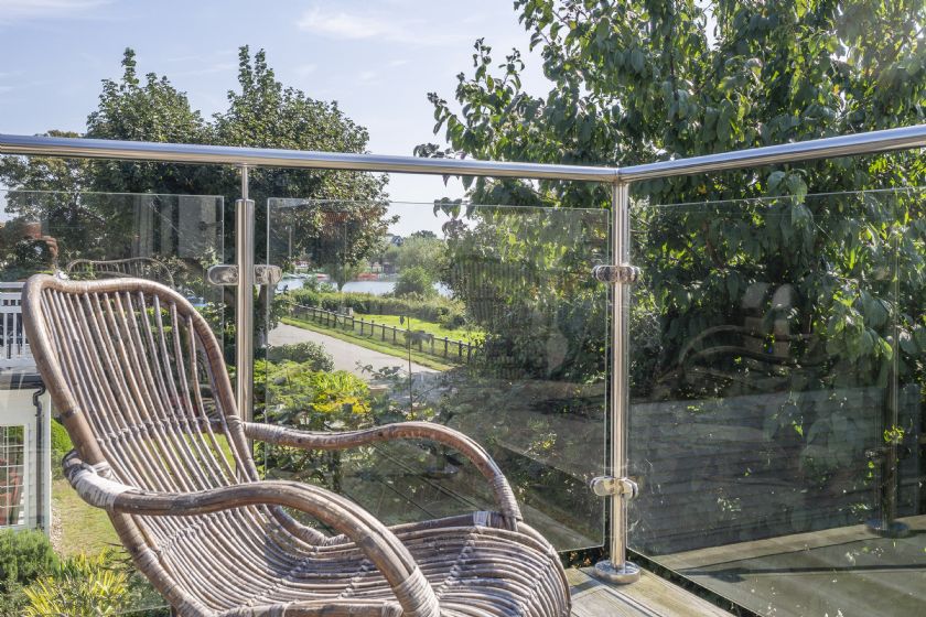 Glass-fronted balcony with wicker chair and lake view