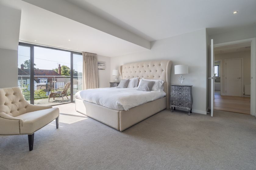 Luxury bedroom with cream upholstered bed and balcony access