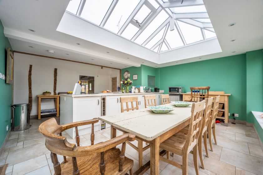 Large kitchen dining room with wood table, skylights and green walls