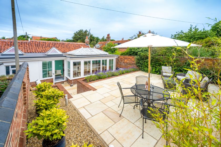 Patio garden view showing conservatory extension and outdoor seating with umbrella