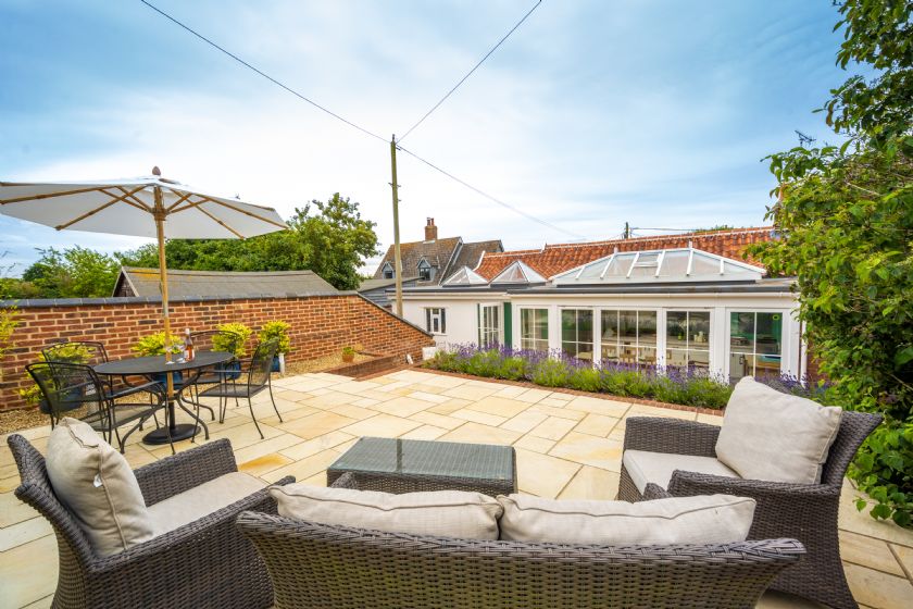 Outdoor patio with both dining area and lounge seating, brick wall and garden views