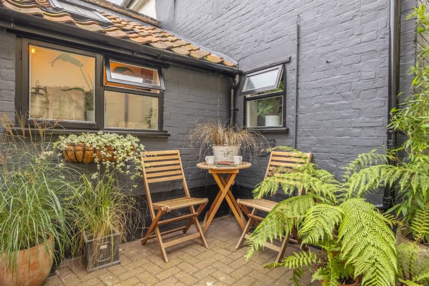 Small private courtyard with wooden chairs, table and potted plants