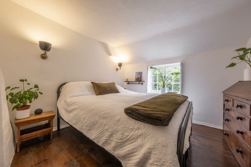 Bright, minimalist bedroom with white walls, iron bed frame and wooden floor
