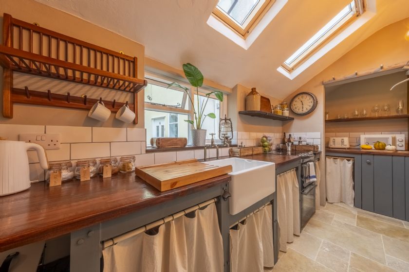 Galley kitchen with wooden countertops, Belfast sink, plate rack and skylights