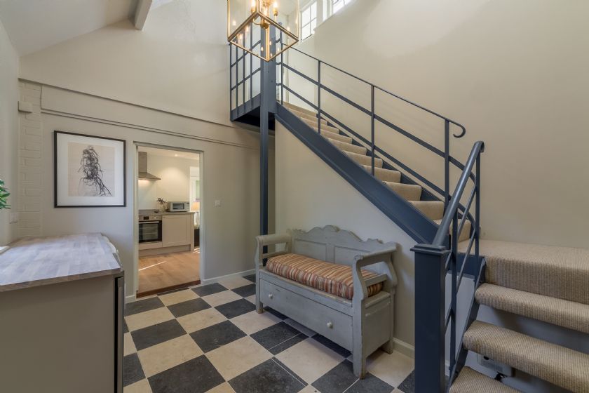 Interior entrance hall with stairs, checkerboard floor, and storage bench