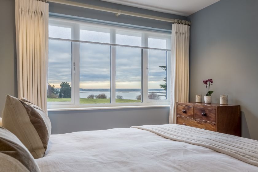 Bedroom with water view from windows and cream/blue color scheme