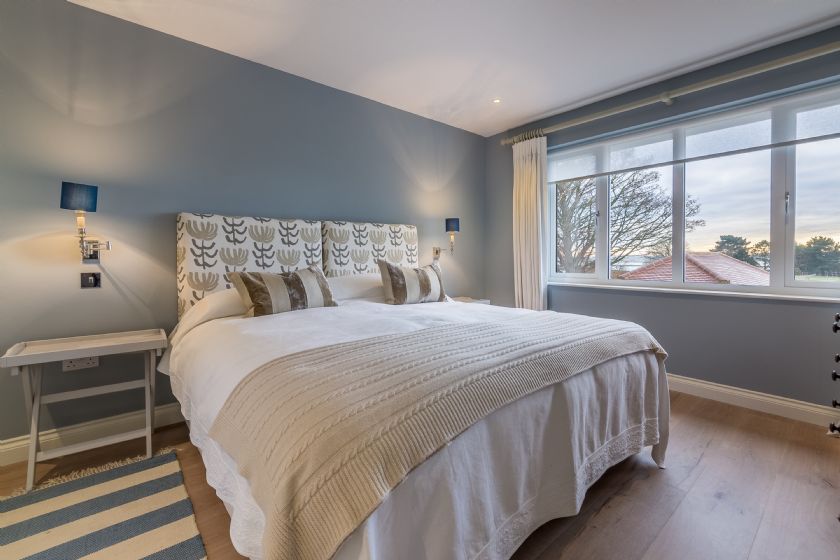 Master bedroom with patterned headboard and blue walls