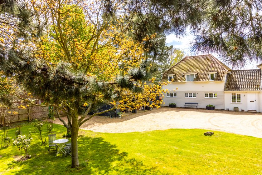 Exterior view of cottage with autumn trees and gravel driveway