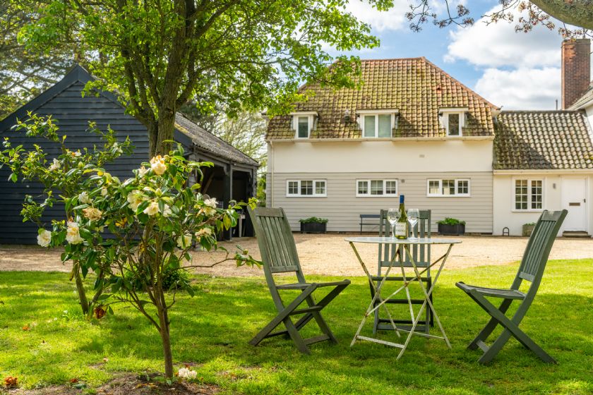 Garden seating area with table, chairs and cottage in background