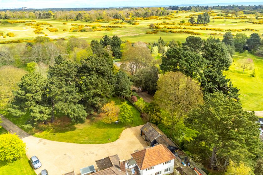 Aerial view of cottage surrounded by trees with countryside beyond