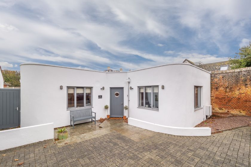 Modern white bungalow with curved walls and grey door