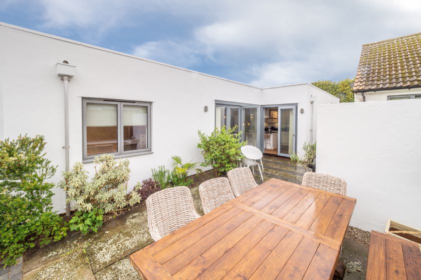 Outdoor patio with wooden table and white walls