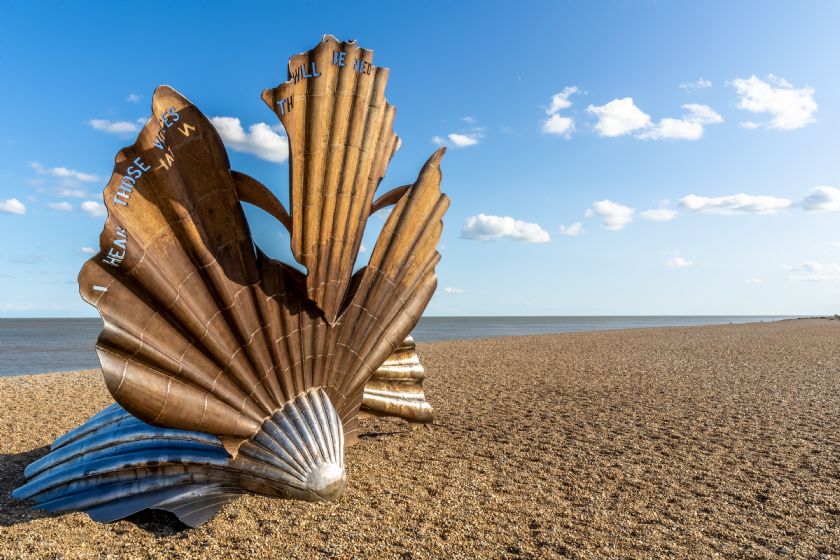 Large metal scallop shell sculpture on beach
