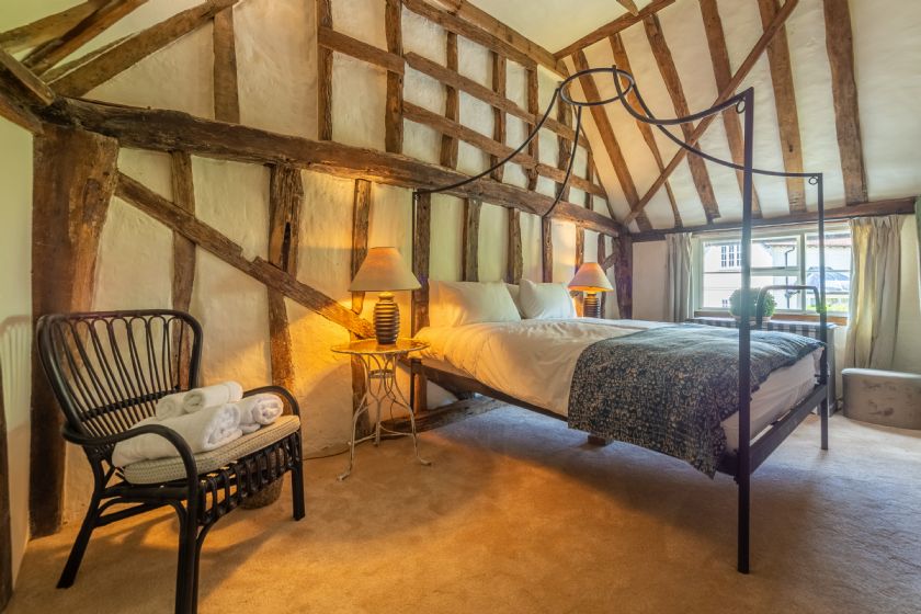 Vaulted ceiling bedroom with exposed beams and iron bed frame