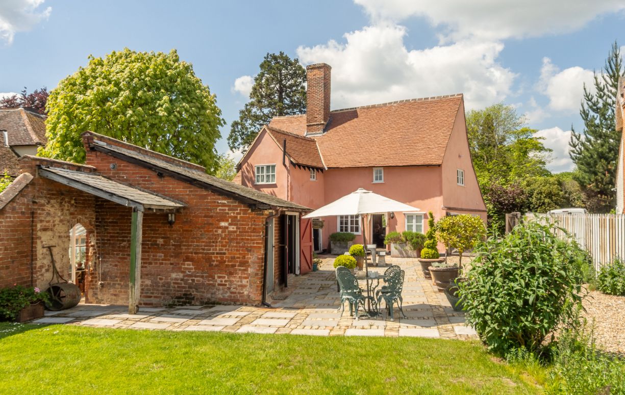 Exterior view of pink farmhouse with brick outbuildings