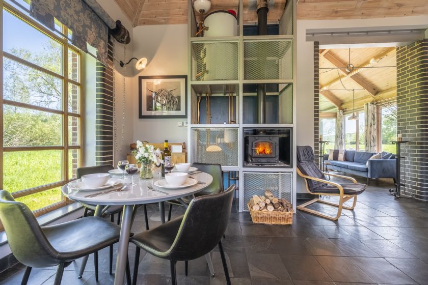 Modern dining area with wood-burning stove and countryside views