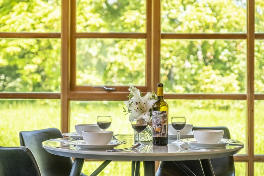Dining table with wine glasses and meadow views