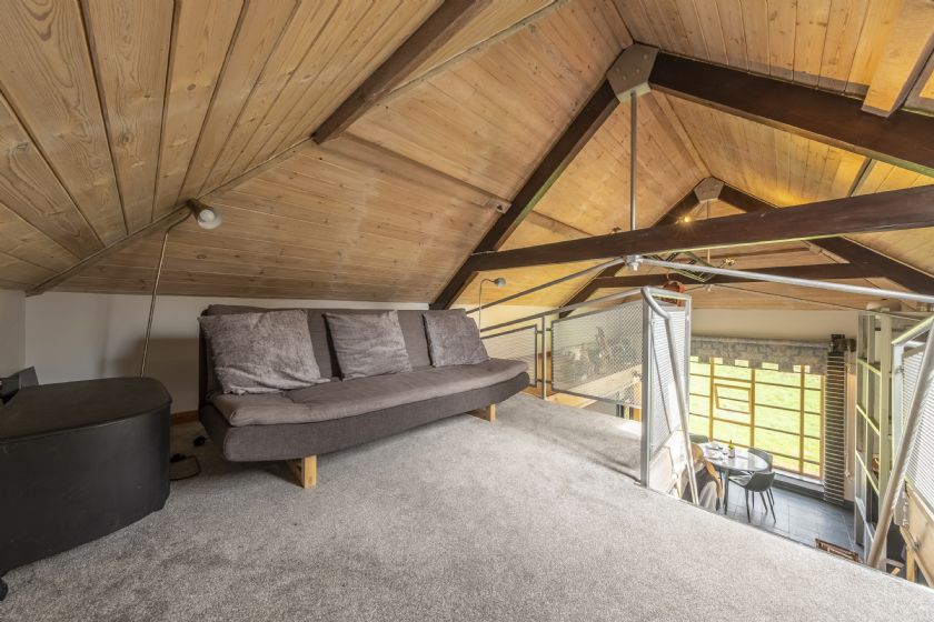 Loft area with wooden beams and grey sofa