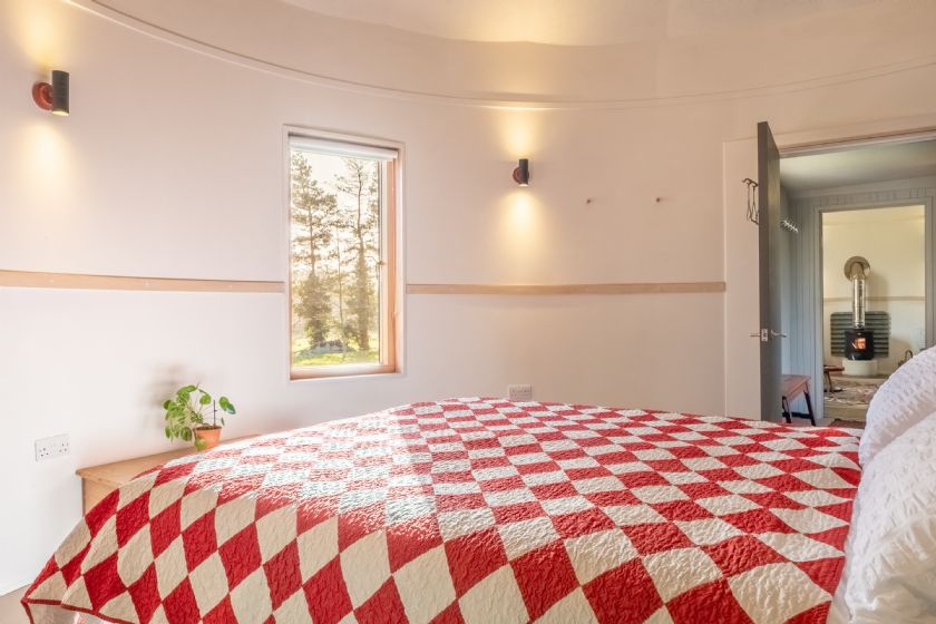Bedroom with red and white checkered quilt in circular room