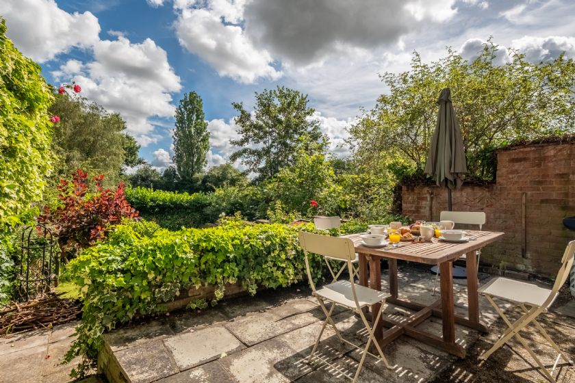 Garden patio with wooden table and lush greenery