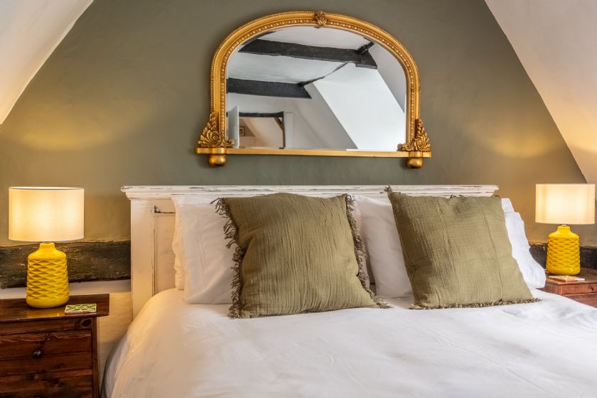 Master bedroom with elegant mirror and green accents