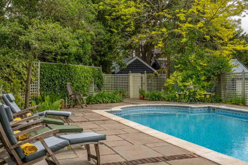 Private swimming pool with loungers and lush garden surroundings