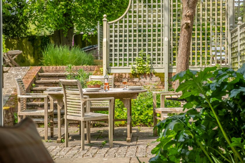 Garden dining area with white lattice fence and trees