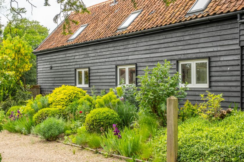 Exterior of dark wood barn conversion with terracotta roof