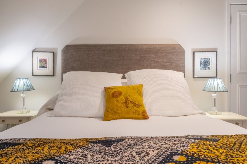 Elegant bedroom with white bedding and yellow accent cushion